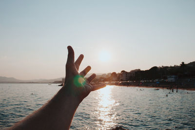 Person hand against sky during sunset