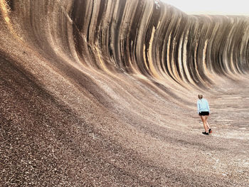 Rear view of woman walking towards rock formation