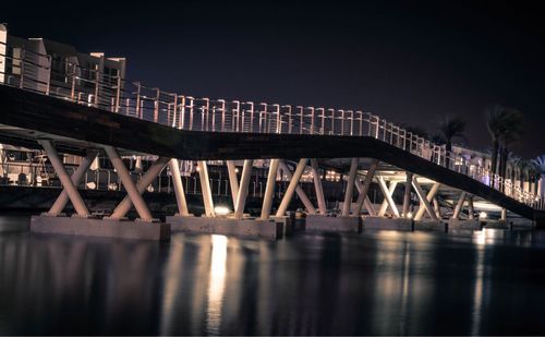 Bridge over river against sky in city at night