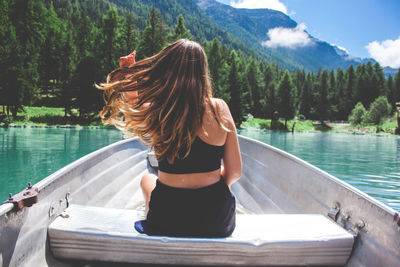 Rear view of woman sitting on boat in river