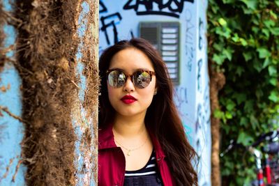 Portrait of young woman against tree trunk