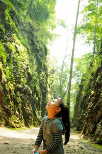 Side view of boy looking away in forest