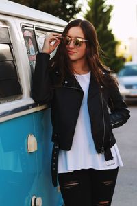 Young woman wearing sunglasses by van on street