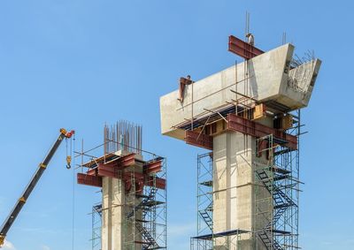 Low angle view of crane against clear blue sky