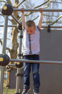 Low angle view of boy hanging on jungle gym