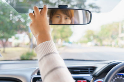 Reflection of woman on rear-view mirror in car