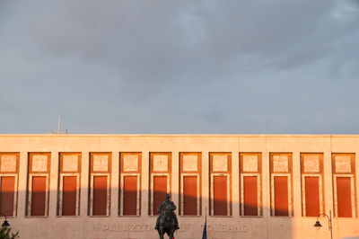 Rear view of people standing by railing against sky