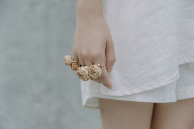 Midsection of young woman wearing rose shape rings against wall