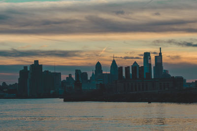 A view of the philadephia skyline over water on a dramatic blue and orange sunse