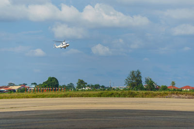 Airplane flying over field against sky