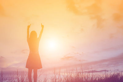 Silhouette woman standing on field against sky during sunset