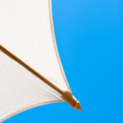 Low angle view of parasol against clear blue sky