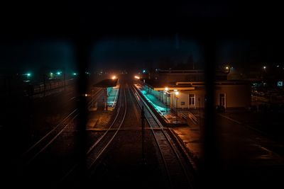 Train on illuminated railroad tracks against sky at night