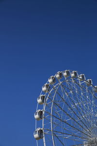 Low angle view of ferris wheel against clear blue sky