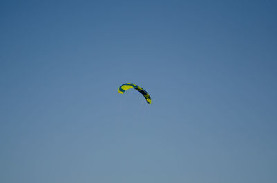 Low angle view of paragliding against clear blue sky