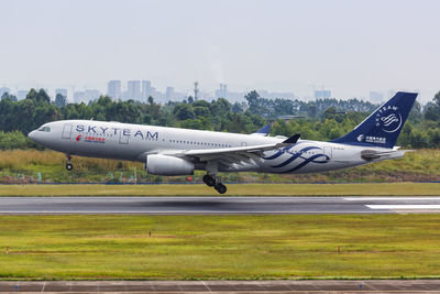 Side view of airplane at airport runway against sky