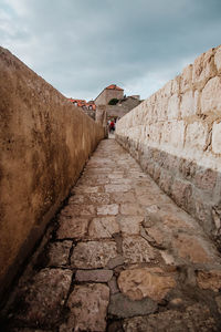 People walking on stone wall against sky