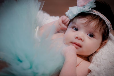 Close-up portrait of cute baby girl lying on bed