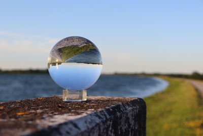 Close-up of a glassball in front of a river 