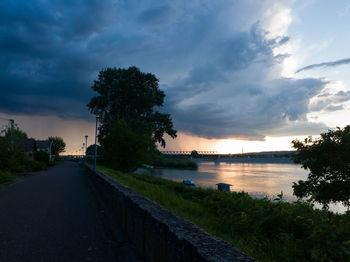 Road by lake against sky during sunset