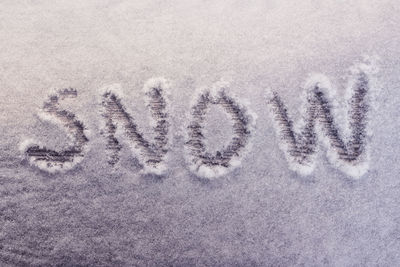 Close-up of frozen text on sand at beach during winter