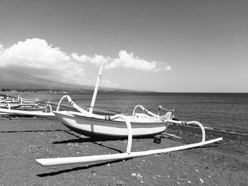 Fishing boats moored on beach against sky