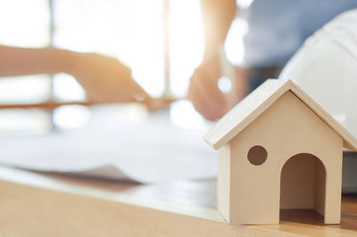 Close-up of model home at desk with architects working in background