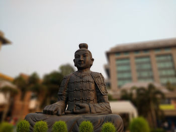 Low angle view of buddha statue against clear sky in park at dusk