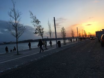 Silhouette people on beach against sky during sunset