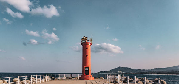 Lighthouse by sea against sky