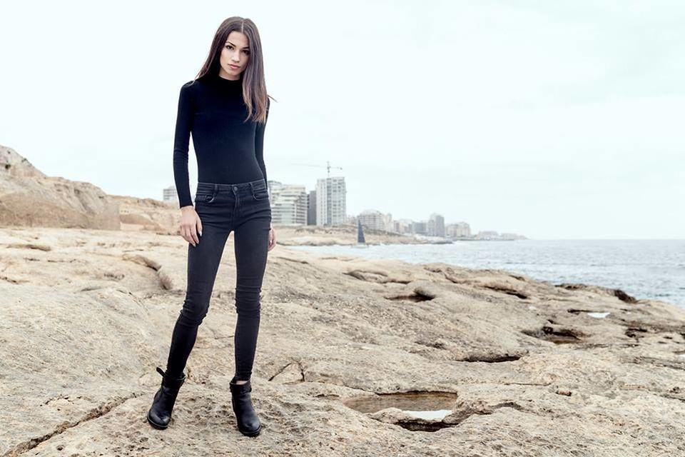 PORTRAIT OF YOUNG WOMAN STANDING ON LAND