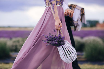 Midsection of woman standing by purple flowering plant