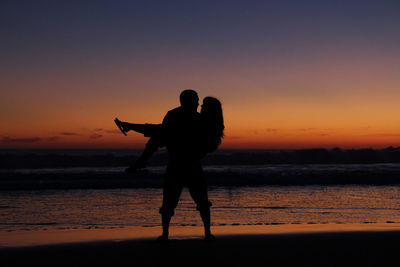 Silhouette of people on beach at sunset