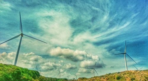 Low angle view of wind turbines on field