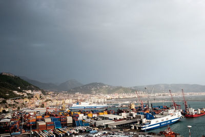 Sailboats moored in harbor by city against sky