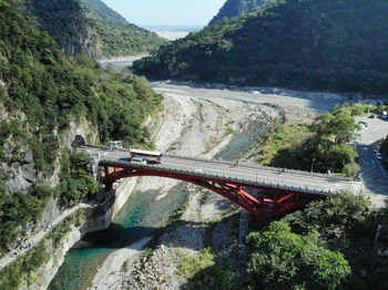 Bridge over river amidst trees against mountains