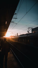 Train at railroad station against sky during sunset