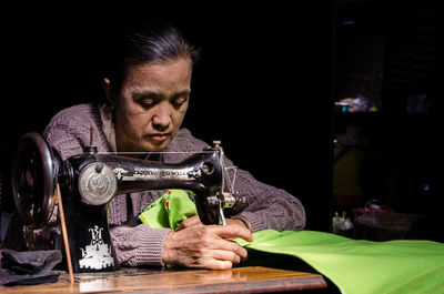 Woman sewing green fabric at workshop