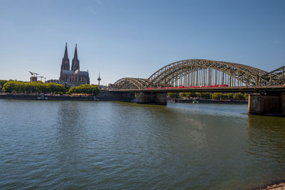Bridge over river in city against clear sky