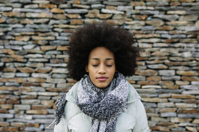 Portrait of woman against brick wall