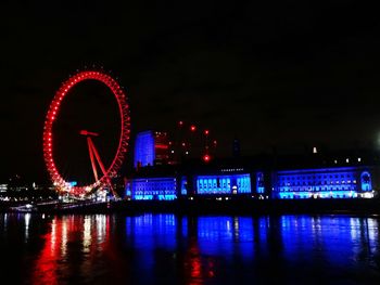 Illuminated ferris wheel in city at night