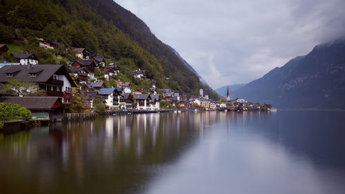 Scenic view of lake by buildings and mountains against sky