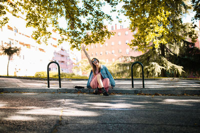 Full length of woman sitting on road in city