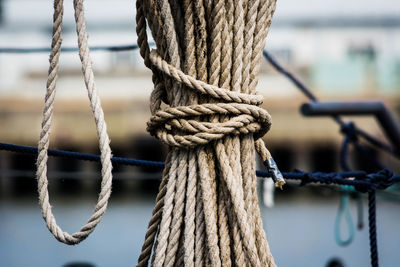 Close-up of tied rope hanging at harbor