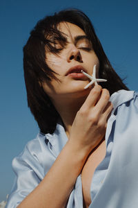 Close-up portrait of a young woman holding blue eyes