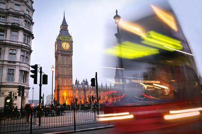 Light trails on city street by big ben at dusk