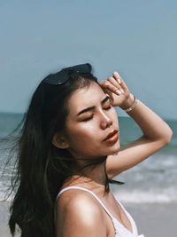 Side view of young woman standing at beach against sky