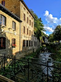 Canal by building against sky