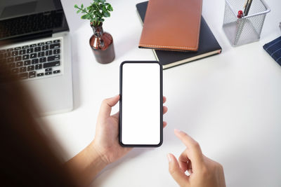 Midsection of person using mobile phone on table