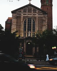 Road by buildings in city at dusk